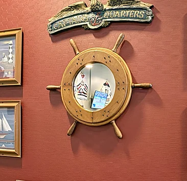 Ship's wheel mirror and sailboat pictures on the Riverboat dining room wall