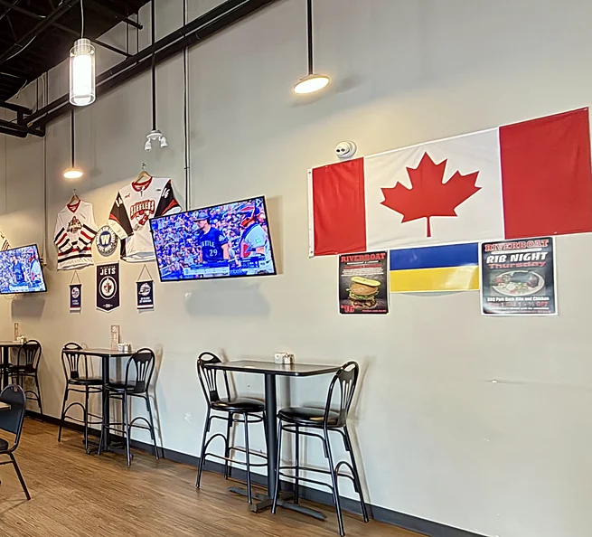 Riverboat dining room with high-top tables, TVs and a Canadian flag
