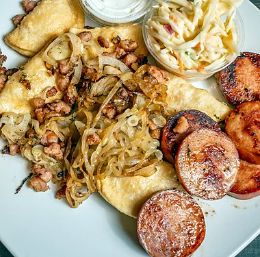 Perogies with fried onions, bacon bits, sausage and sour cream