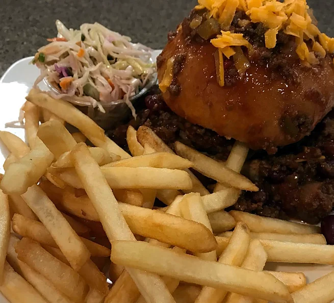 Chili burger topped with cheddar, served with fries and coleslaw
